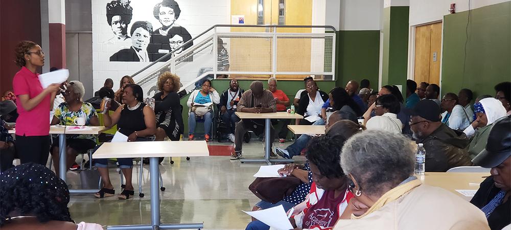 A group of people gather in a gym for an information session