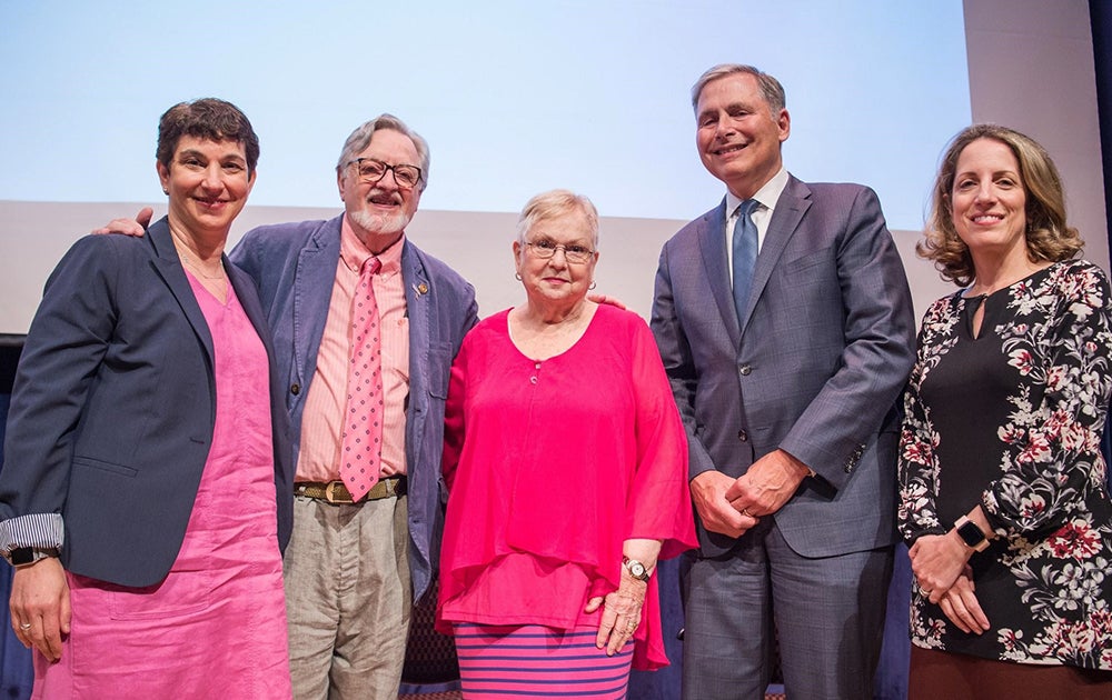 A group of five people stand together