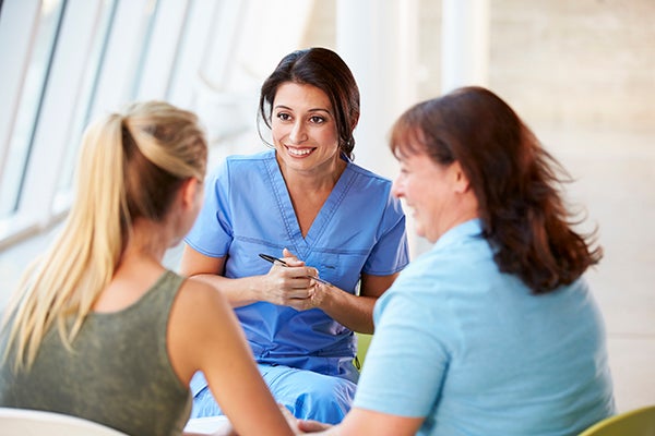 A doctor talks with a mother and daughter during a cancer screen visit.