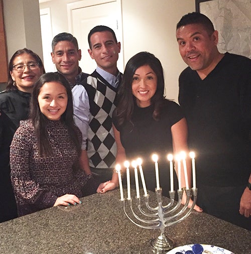 A group of people stand around a lighted menorah