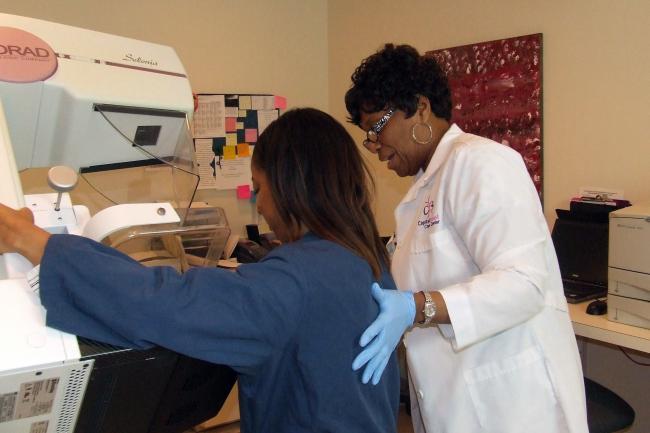 A technician administers a mammogram to a woman