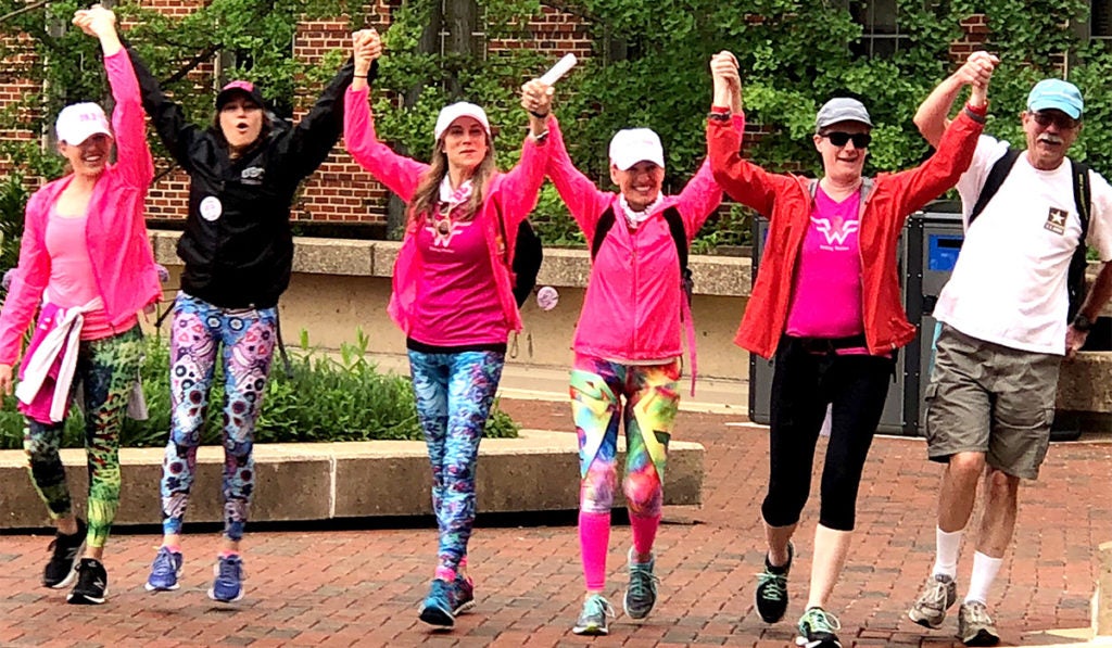 A group of people hold hands in triumph as they finish a charity walk