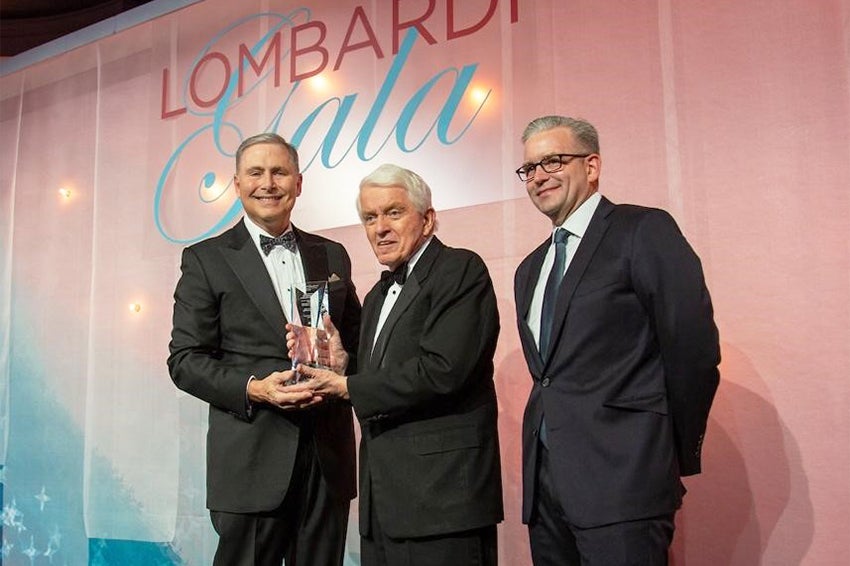 Three men stand together before the Lombardi Gala audience