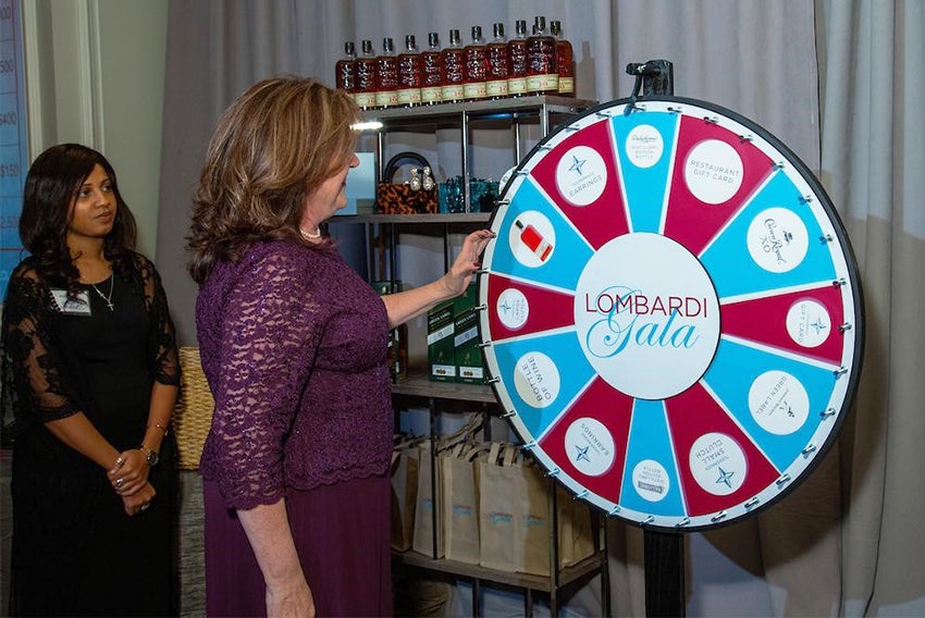 A woman spins a prize wheel as another woman looks on