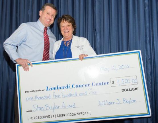 Two people hold a giant check