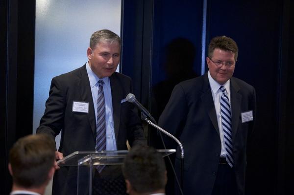 Two men stand together behind a podium