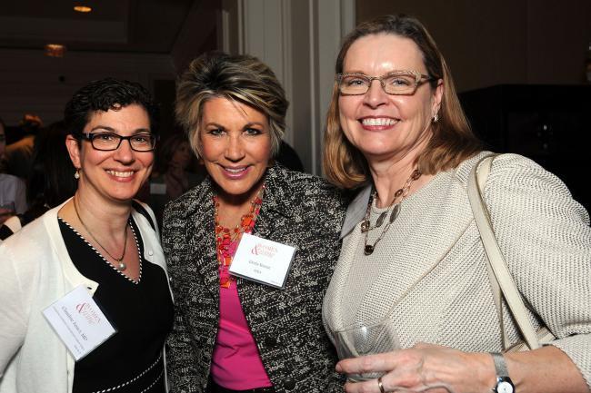 Three women stand together at Women and Wine event
