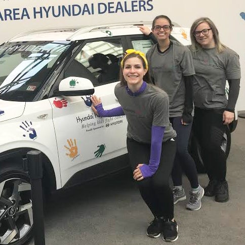 Three women stand next to a car