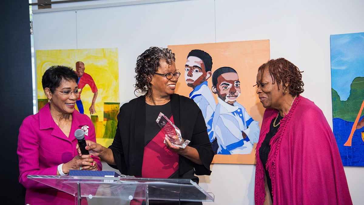 Three women stand behind a podium