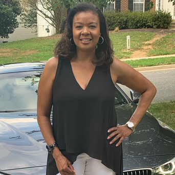 Glynda Brown stands outdoors in front of a car