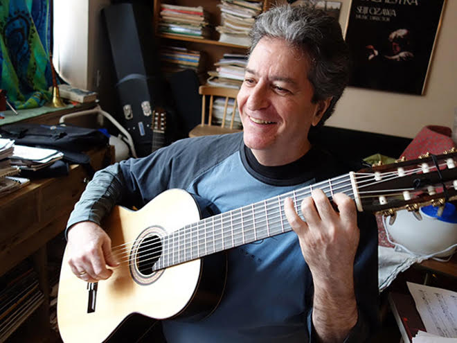 Andrew Shulman plays a guitar in an office