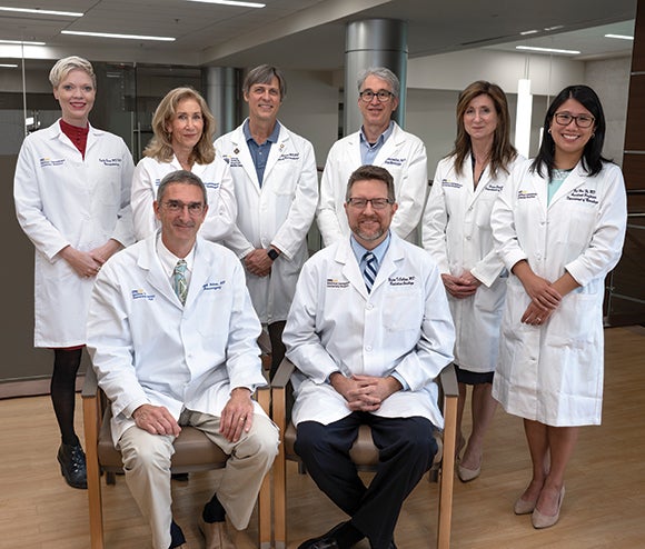 A group of doctors in their white coats stand together in a hospital setting