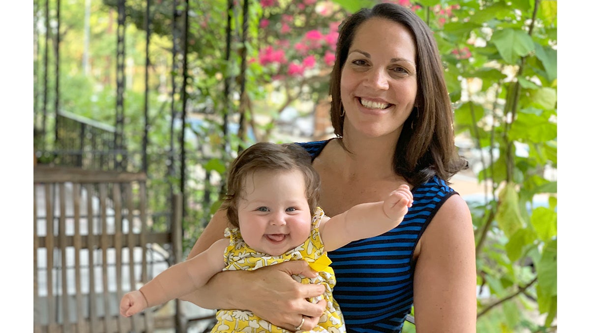 Brandi Farmer holds her baby daughter; greenery is in the background