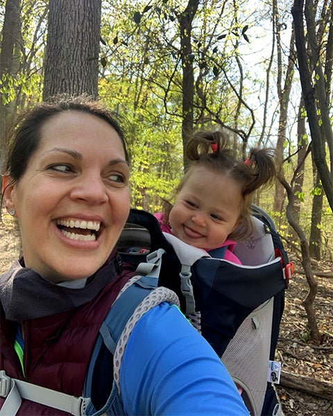 Brandi Farmer smiles back at her baby daughter who is enjoying her ride in a baby backpack carrier