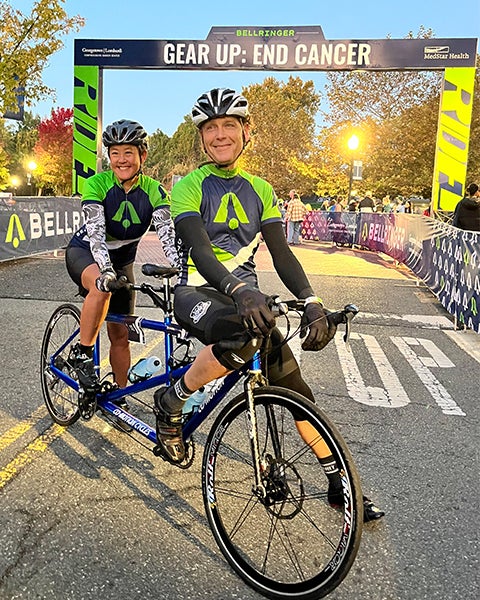 Two people ride a tandem bike