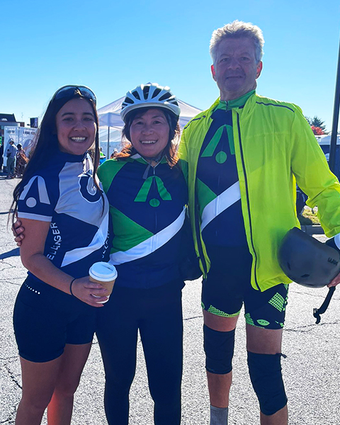 Three individuals stand together in cycling gear