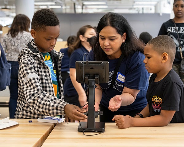 Ayesha assists students using a microscope