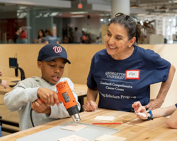 Olga Rodriguez works with a student using a glue gun