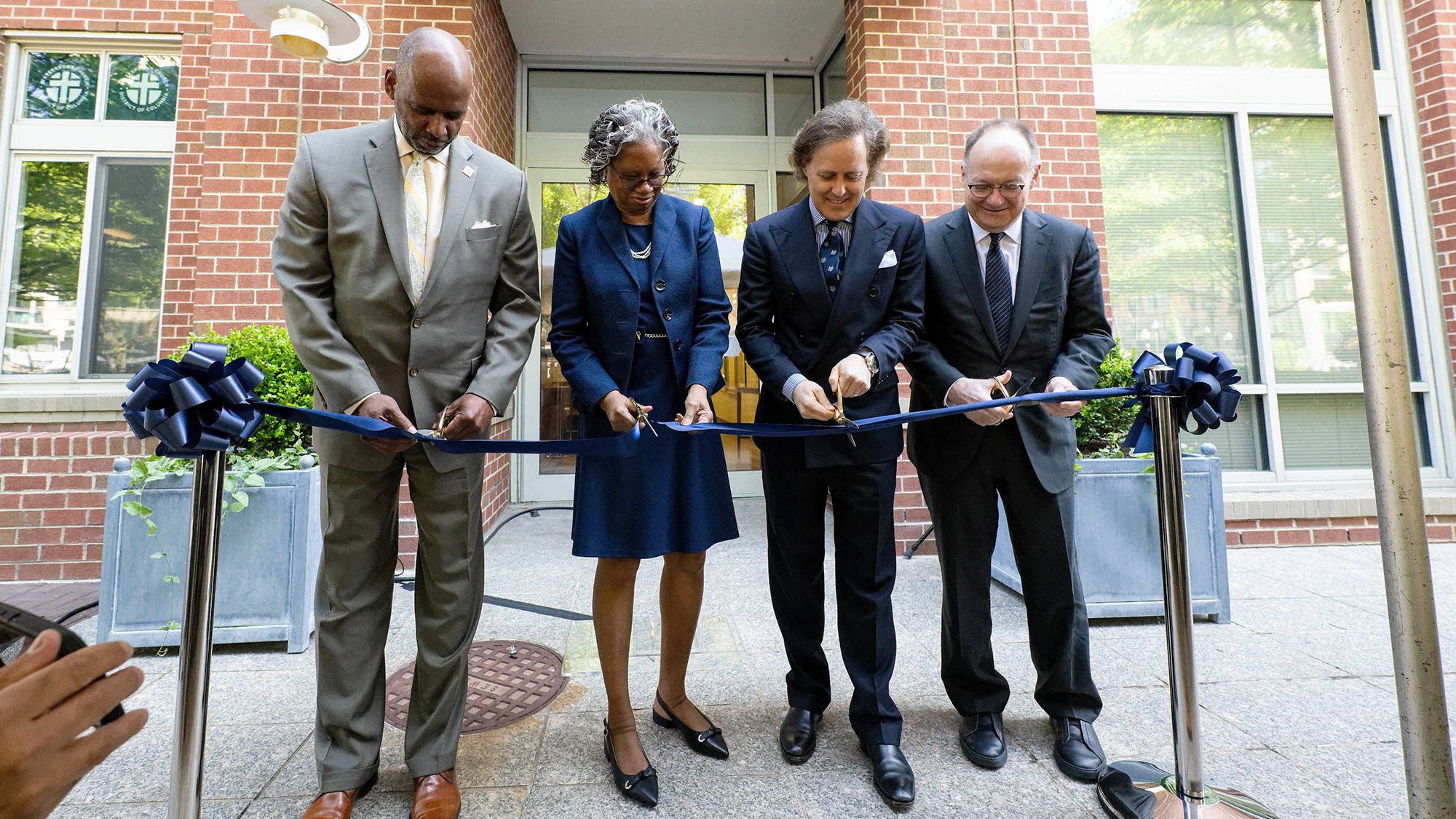Four individuals cut a ceremonial ribbon for the opening of the Ralph Lauren Center