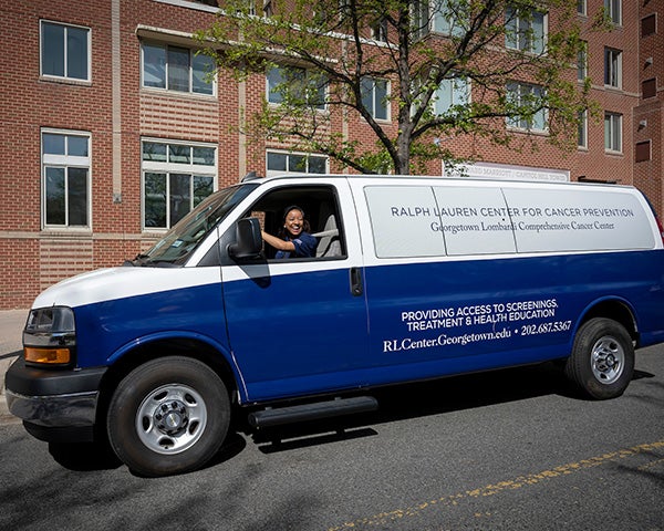 A 12 passenger van wrapped in blue and white with the center logo on the side