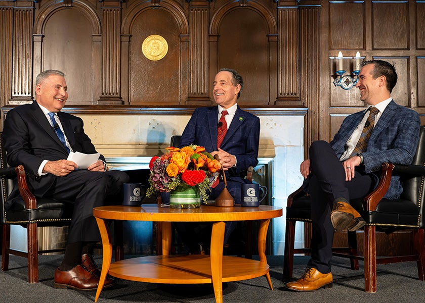 Dr. Weiner, Raskin and Dr. Roswarski sit in chairs around a table onstage