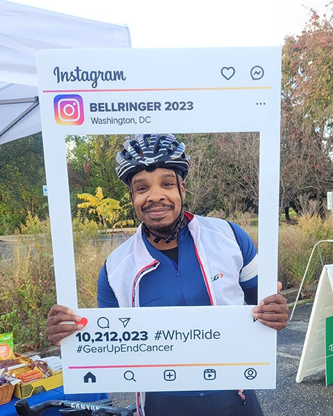 Clayton Douglas holds a cardboard frame for an Instagram image while at a rest stop during the ride