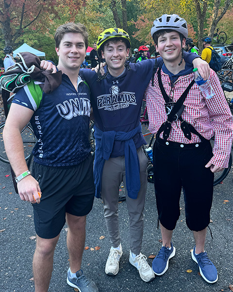 Three people stand together wearing biking gear