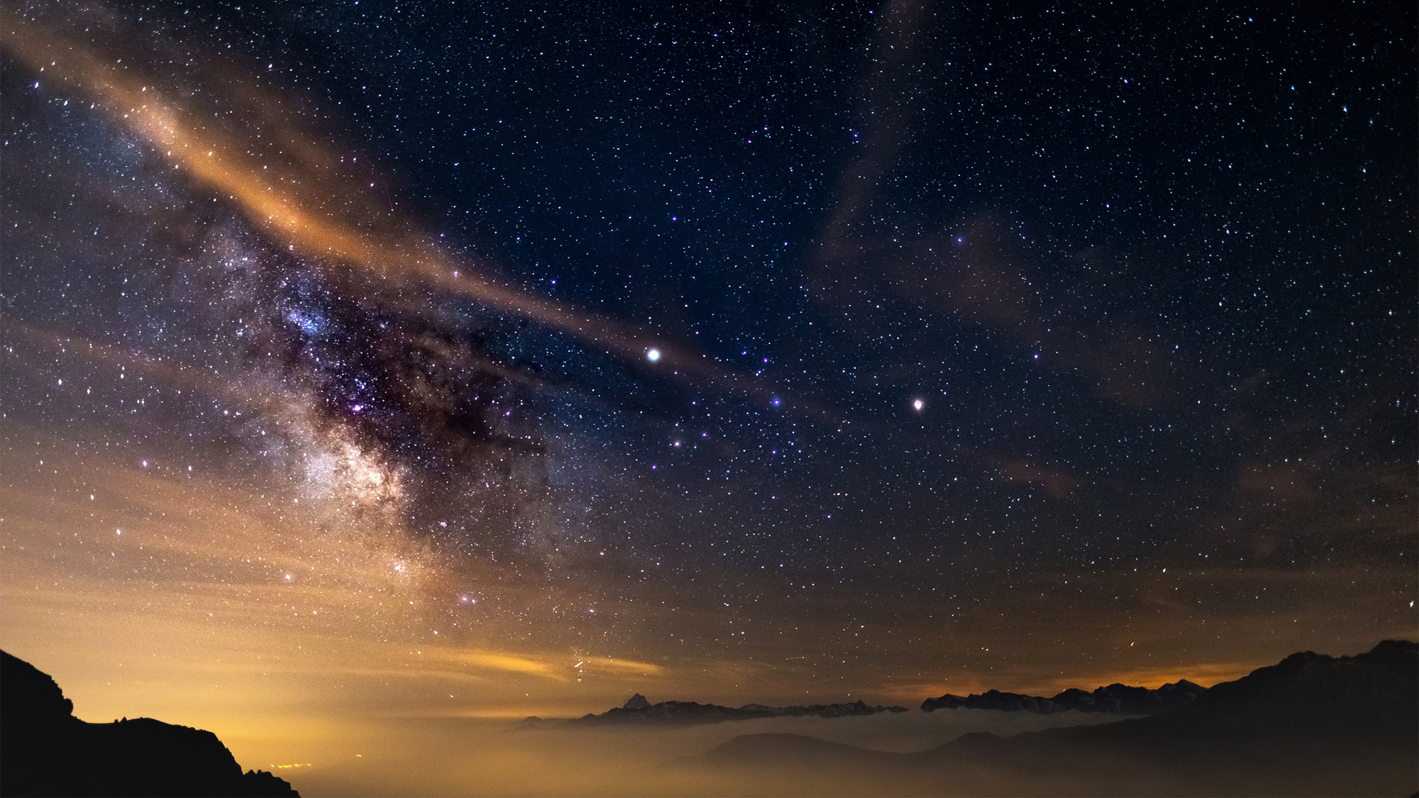 A view of space with the Milky Way, planets and stars visible in the dark sky