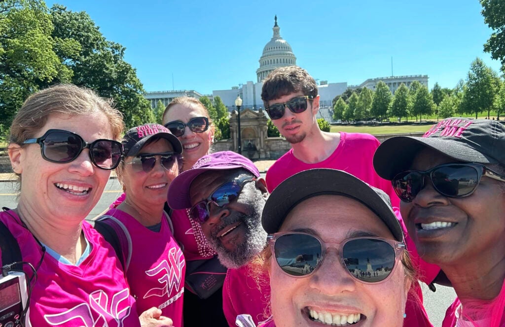 Walkers stand together in pink T-shirts with the Capitol Building behind them