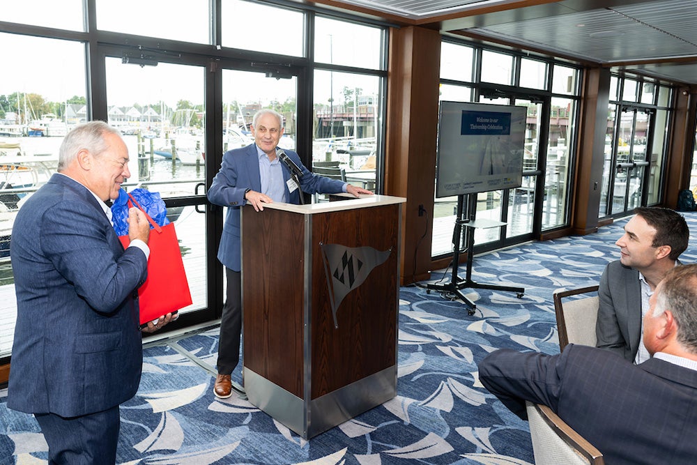 Dr. Atkins, who is standing at a podium, receives a red bag from a man