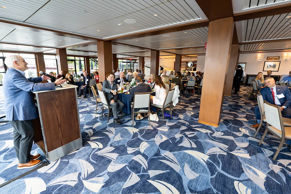 A view of the room in which the luncheon took place with a podium in front and tables full of people