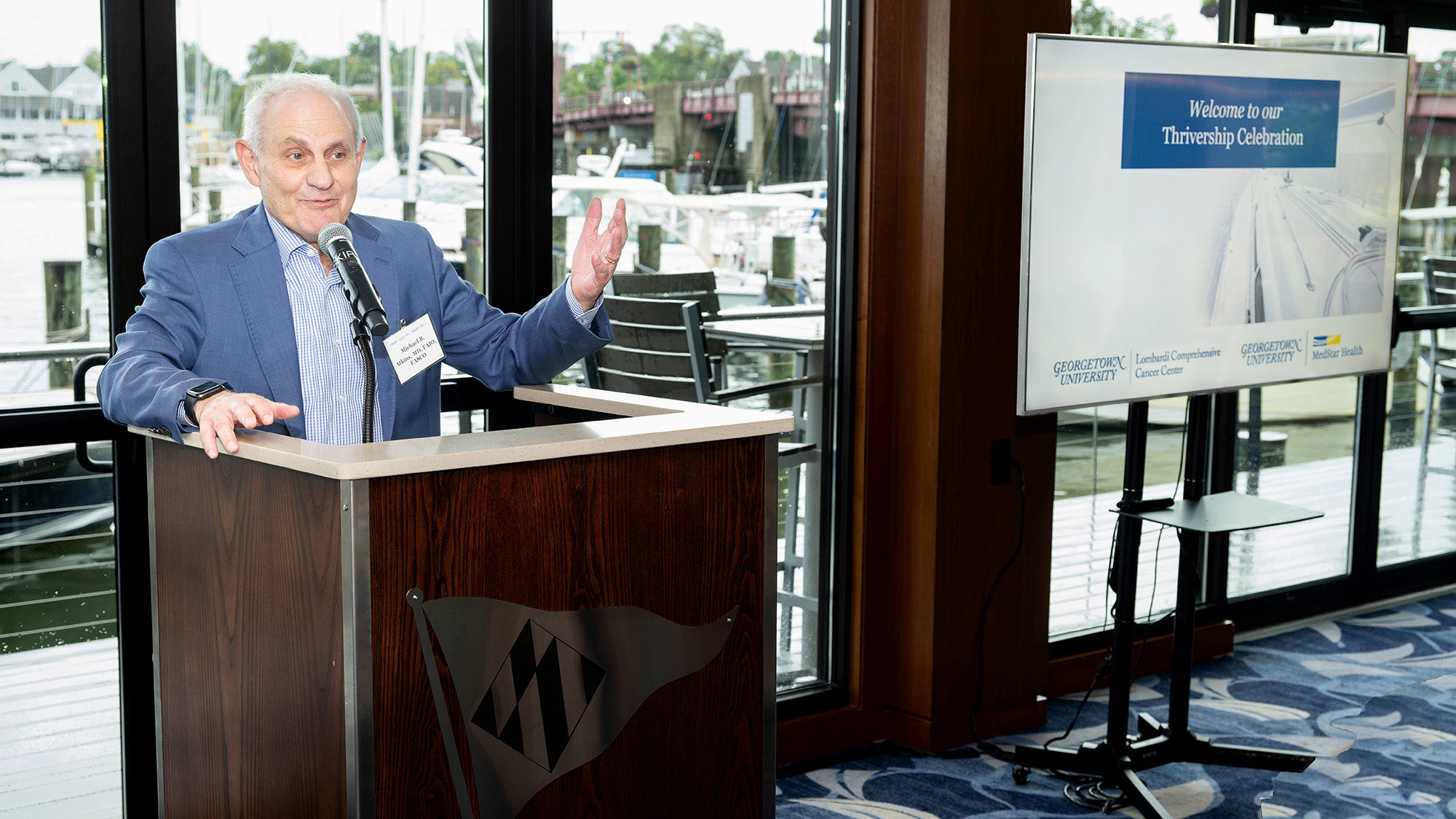 Michael Atkins speaks from a podium at the Yacht Club