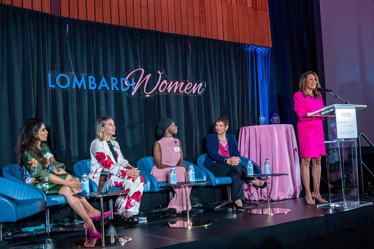 The event's four panelists sit in chairs as they are introduced by the moderator