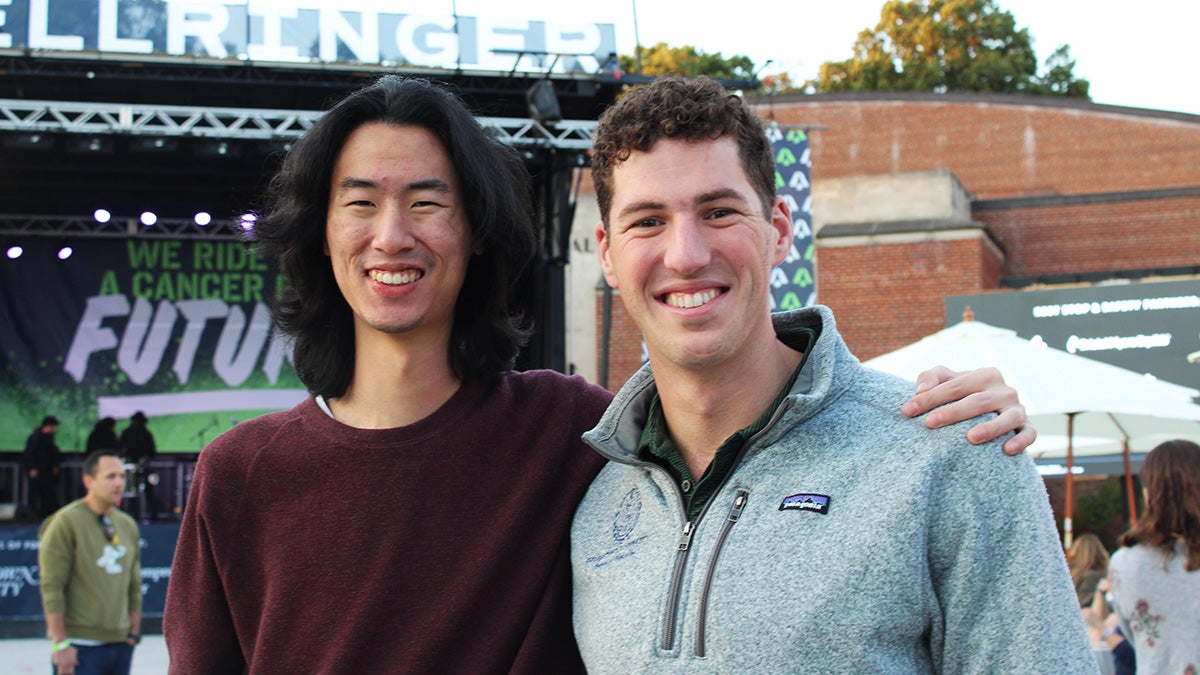 Two students stand together with the BellRinger opening ceremony stage in the background