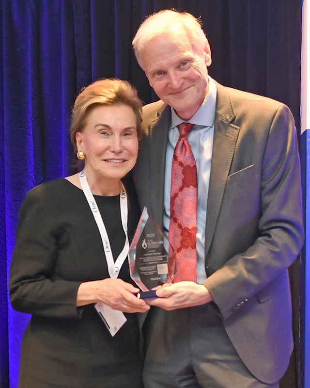 Jeanne Ruesch and John Marshall stand side by side with Ruesch holding her glass Luminary Award