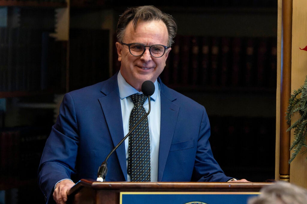 Norm Beauchamp speaks from a podium in Riggs Library