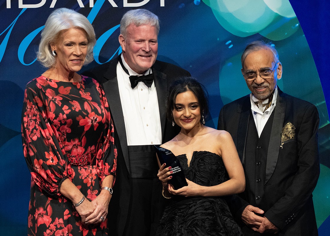 Laurie Hodges Lapeyre and Walter Hodges, Emily Bhatnagar and her father stand onstage at the gala