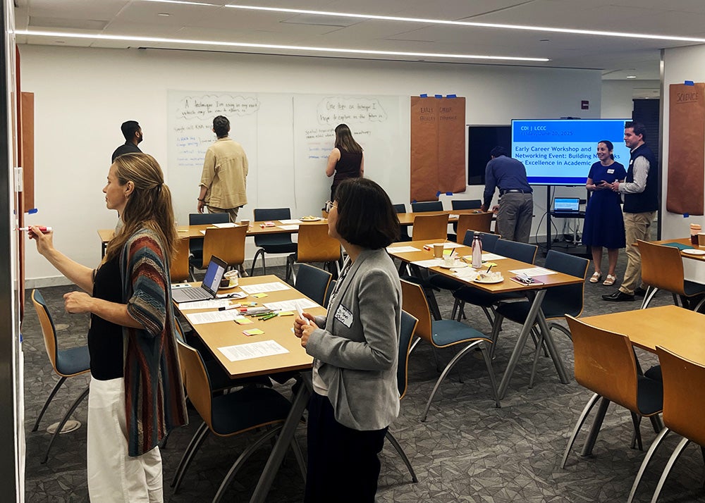 Attendees add sticky notes to various posters on the walls of the conference room