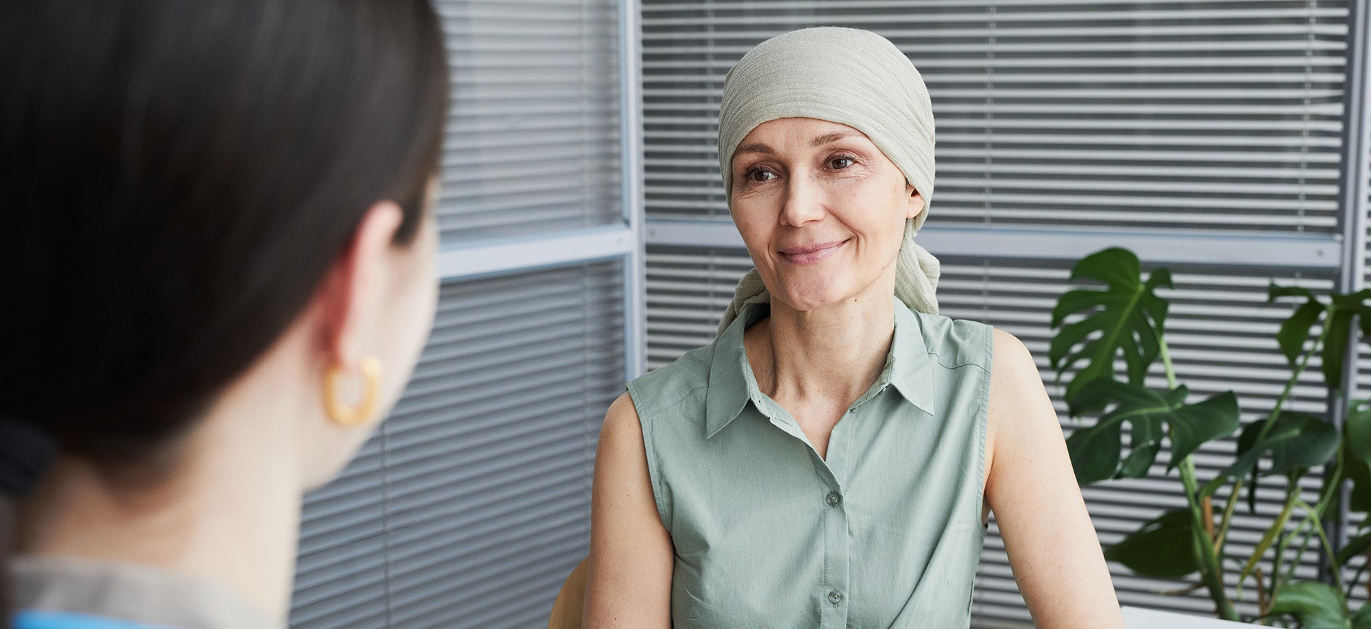A breast cancer patient wearing a headscarf listens to a medical professional