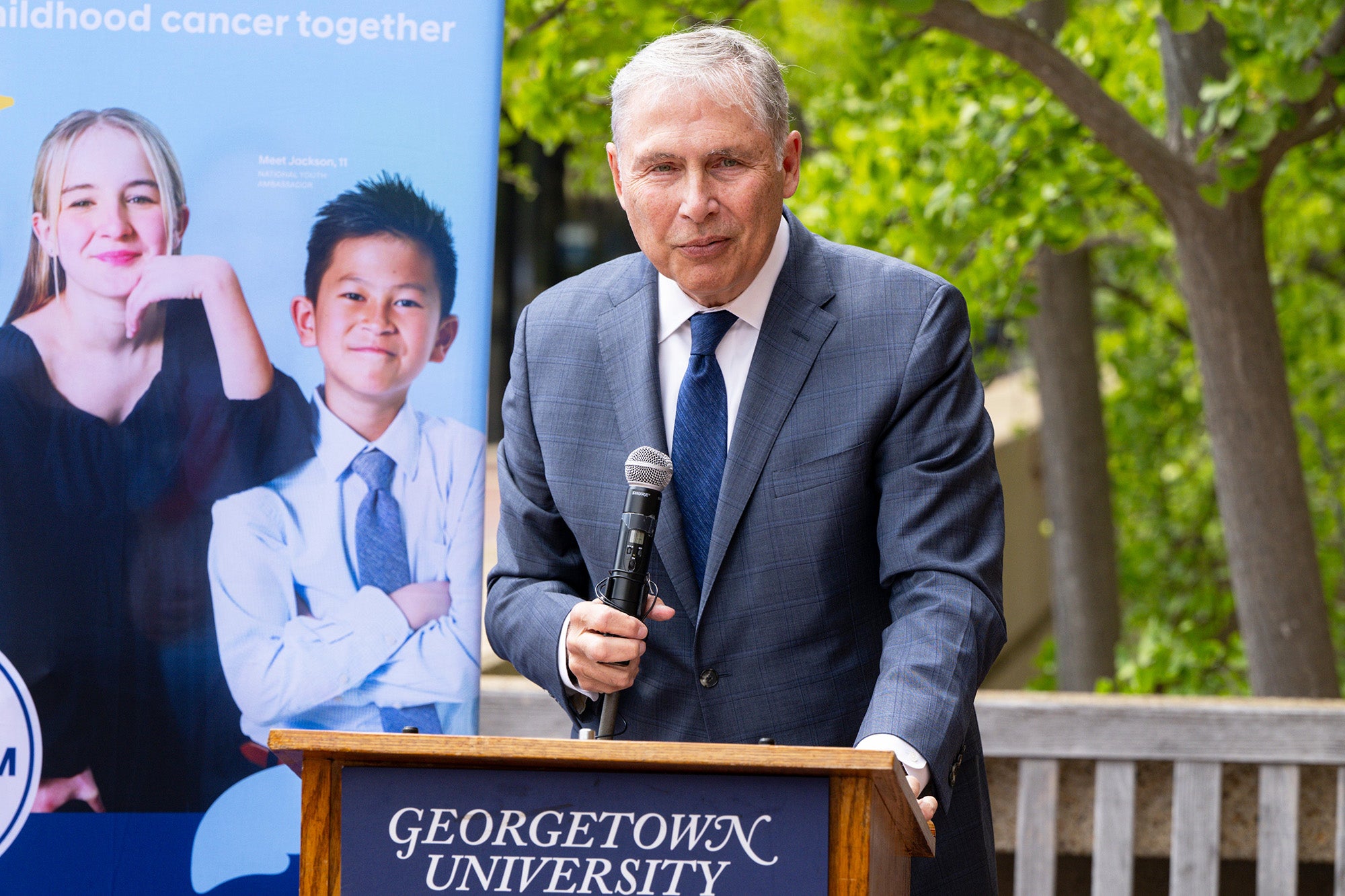 Lou Weiner speaks from a podium outdoors