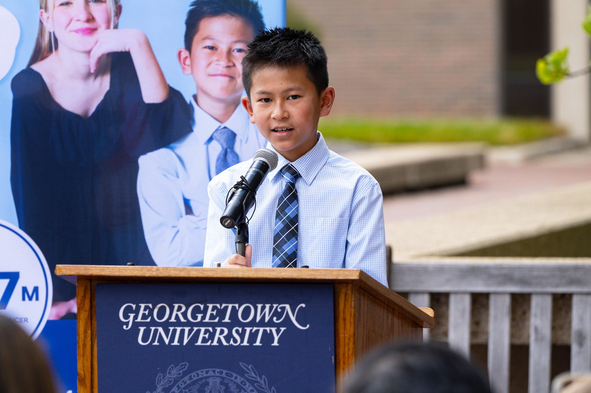 A young boy speaks from a podium outdoors
