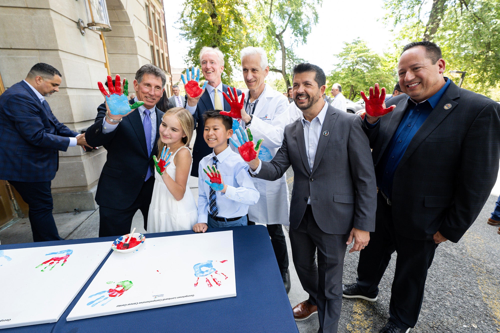 A group of adults and children hold up their painted palms