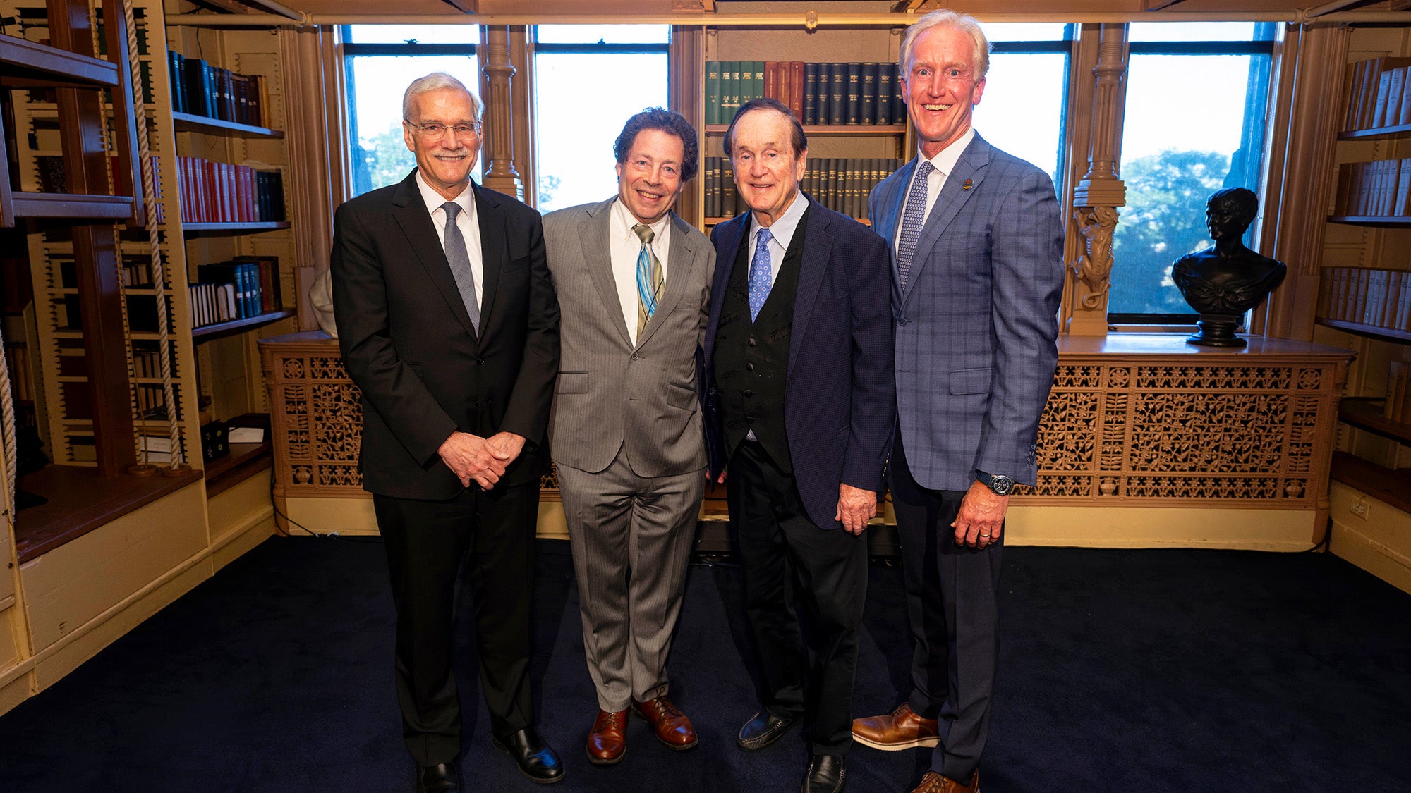 Four men stand together in Riggs Library