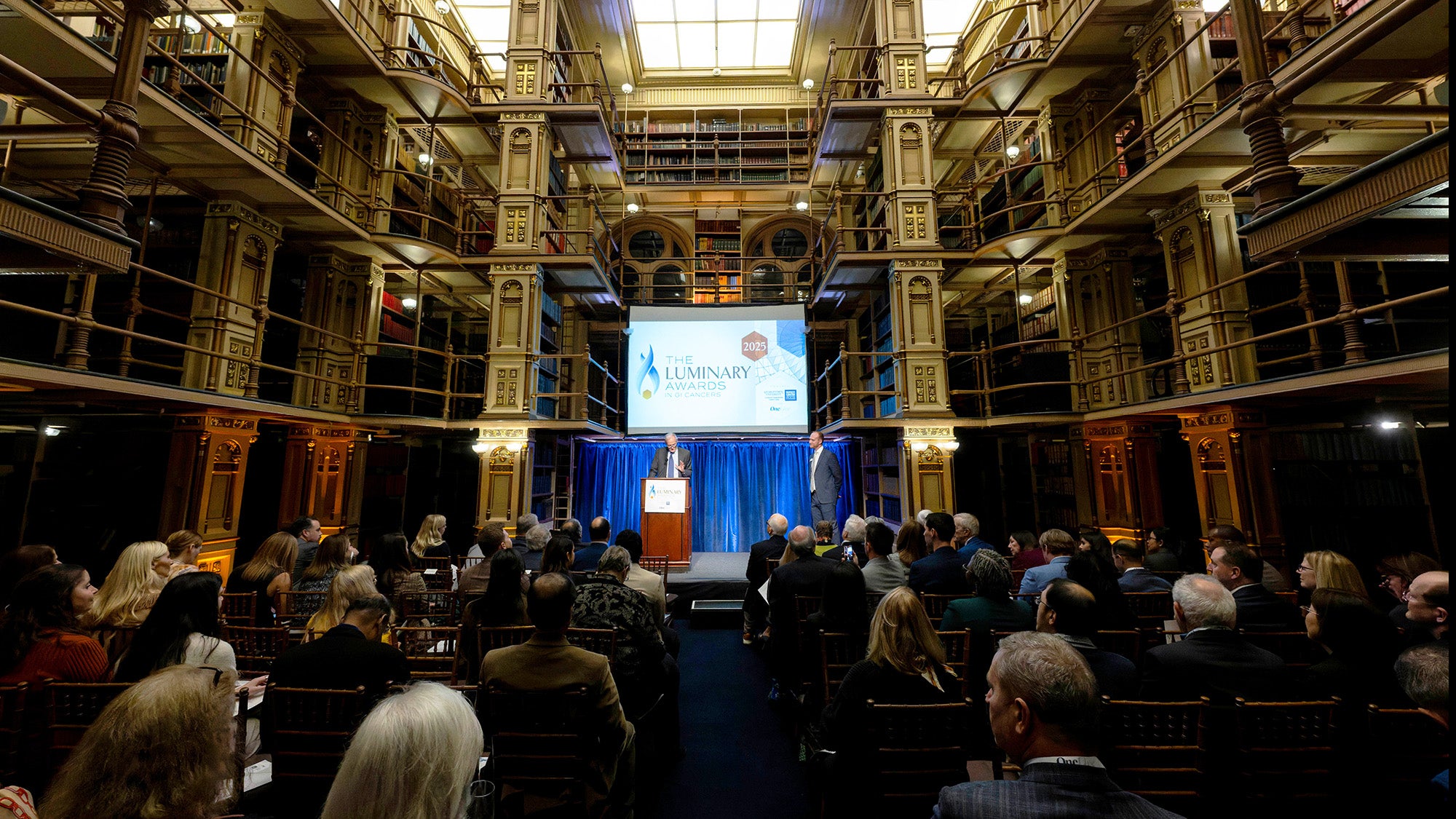 A view of the Riggs Library stacks and rows of people seated in chairs
