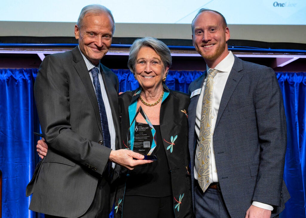 Three individuals stand together, one of them is Bo Aldige holding an award