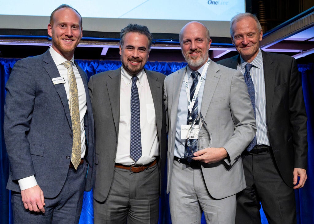 Four individuals stand together, one of them is Scott Kopetz holding an award