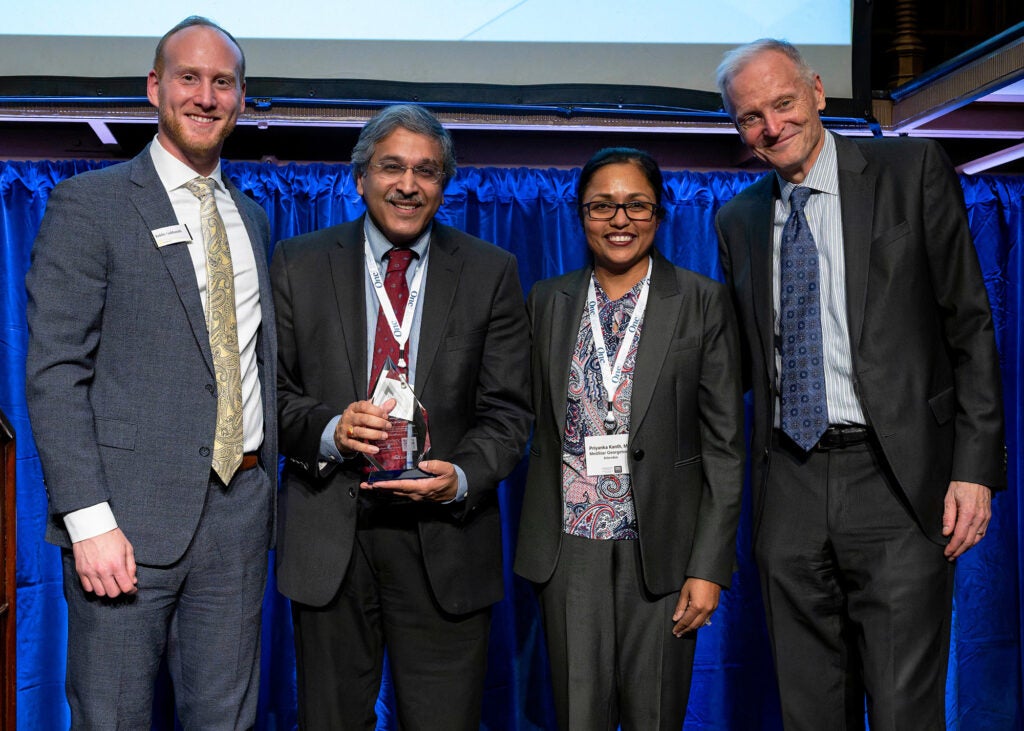 Four individuals stand together, one of them is Anil Rustgi holding an award