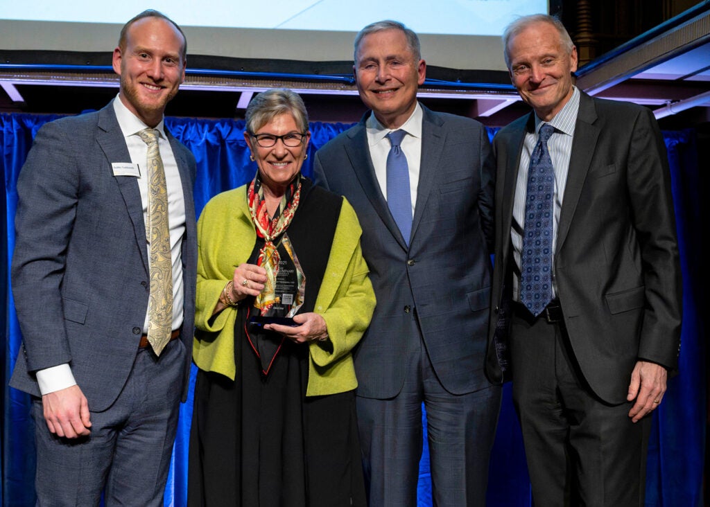 Four individuals stand together, one of them is Margaret Tempero holding an award