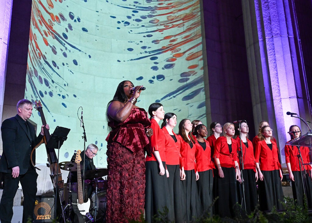 Nova Payton sings with the children's chorus performers standing in a semi-circle onstage with a band behind them