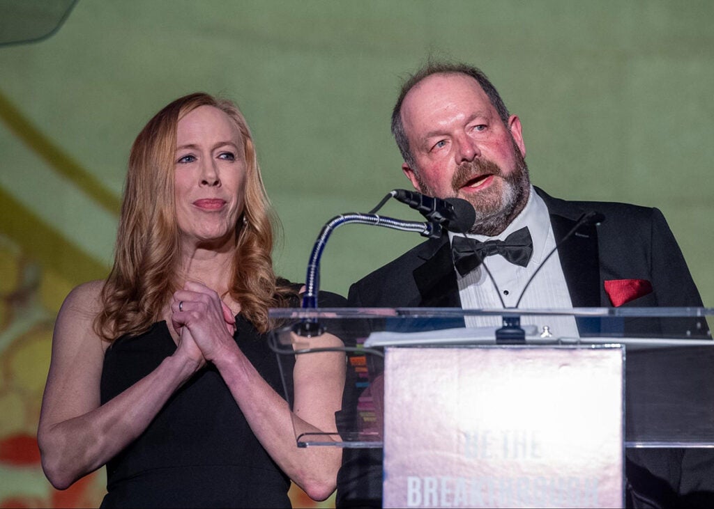 Kim Strassel  and Nick Van Dyke speak from behind a podium onstage
